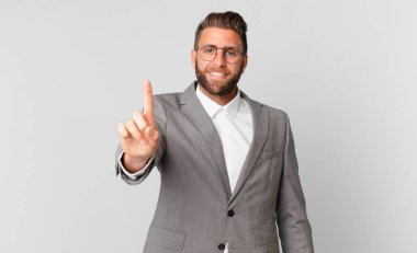 young handsome man smiling proudly and confidently making number one. business concept