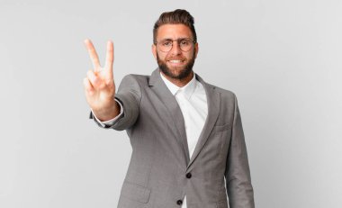 young handsome man smiling and looking friendly, showing number two. business concept