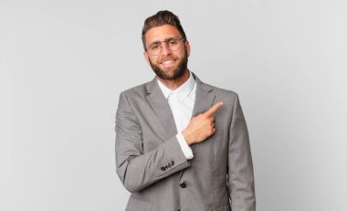 young handsome man smiling cheerfully, feeling happy and pointing to the side. business concept