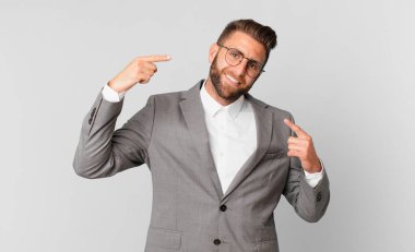 young handsome man smiling confidently pointing to own broad smile. business concept