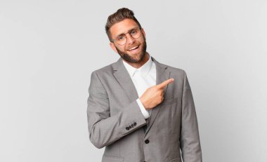 young handsome man looking excited and surprised pointing to the side. business concept
