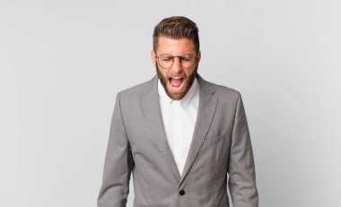 young handsome man shouting aggressively, looking very angry. business concept