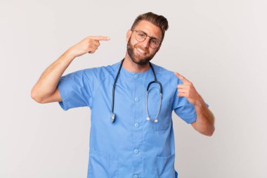 young handsome man smiling confidently pointing to own broad smile. nurse concept