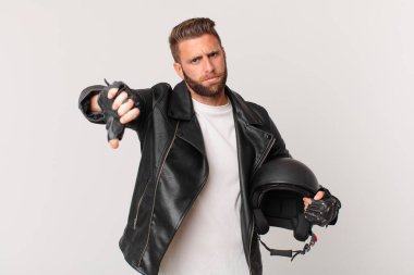 Genç ve yakışıklı bir adam kendini kötü hissediyor, baş parmağını kaldırıyor. Motosiklet kaskı konsepti