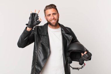Genç yakışıklı adam kendini mutlu hissediyor, iyi bir jestle onaylıyor. Motosiklet kaskı konsepti