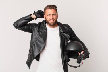 Genç ve yakışıklı bir adam stresli, endişeli ya da korkmuş hissediyor. Elleri başının üstünde. Motosiklet kaskı konsepti