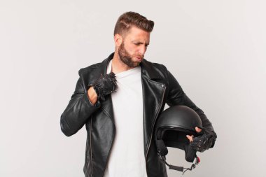 Genç ve yakışıklı adam stresli, endişeli, yorgun ve hayal kırıklığına uğramış hissediyor. Motosiklet kaskı konsepti