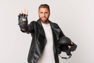 Genç yakışıklı adam gülümsüyor ve arkadaş canlısı görünüyor, dört numarayı gösteriyor. Motosiklet kaskı konsepti