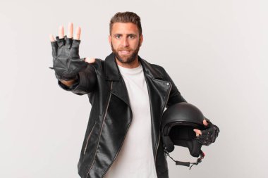 Genç yakışıklı adam gülümsüyor ve arkadaş canlısı görünüyor, beş numarayı gösteriyor. Motosiklet kaskı konsepti