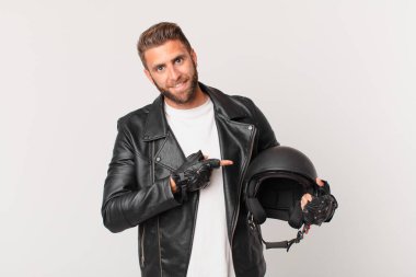 Genç yakışıklı adam neşeyle gülümsüyor, mutlu hissediyor ve bir tarafı işaret ediyor. Motosiklet kaskı konsepti