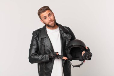 Genç yakışıklı adam neşeyle gülümsüyor, mutlu hissediyor ve bir konsept gösteriyor. Motosiklet kaskı konsepti