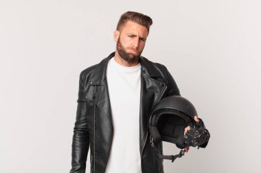 Genç ve yakışıklı bir adam üzgün ve mızmızlanıyor. Mutsuz bir bakışı var ve ağlıyor. Motosiklet kaskı konsepti