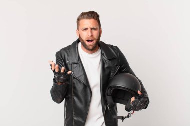 Genç yakışıklı adam umutsuz, sinirli ve stresli görünüyor. Motosiklet kaskı konsepti