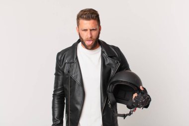 young handsome man feeling disgusted and irritated and tongue out. motorbike helmet concept