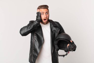 young handsome man feeling happy, excited and surprised. motorbike helmet concept
