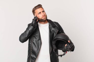 young handsome man thinking, feeling doubtful and confused. motorbike helmet concept
