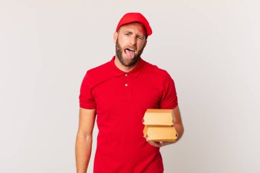 young handsome man with cheerful and rebellious attitude, joking and sticking tongue out burger delivering concept