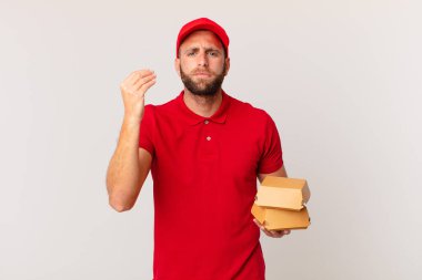 young handsome man making capice or money gesture, telling you to pay burger delivering concept