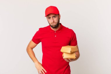 young handsome man looking puzzled and confused burger delivering concept