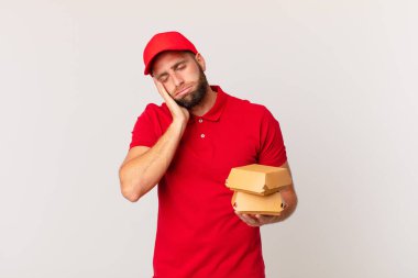 young handsome man feeling bored, frustrated and sleepy after a tiresome burger delivering concept