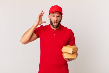 young handsome man screaming with hands up in the air burger delivering concept