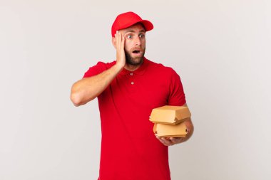 young handsome man feeling happy, excited and surprised burger delivering concept