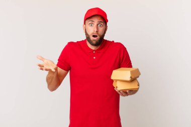 young handsome man feeling extremely shocked and surprised burger delivering concept
