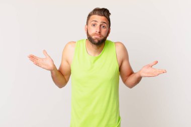 Genç yakışıklı adam şaşkın, şaşkın ve şüpheci hissediyor. fitness konsepti