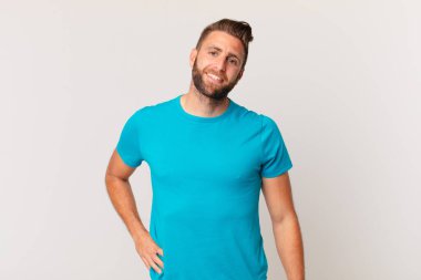 Genç yakışıklı adam mutlu bir şekilde gülümsüyor, eli kalçasında ve kendinden emin. fitness konsepti