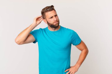 Kafası karışmış, kafası karışmış, kaşınan genç, yakışıklı bir adam. fitness konsepti