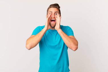 Genç yakışıklı adam mutlu hissediyor, elleri ağzının kenarında bağırıyor. fitness konsepti