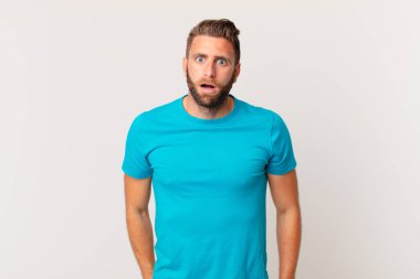 Genç ve yakışıklı bir adam çok şaşırmış ya da şaşkın görünüyor. fitness konsepti