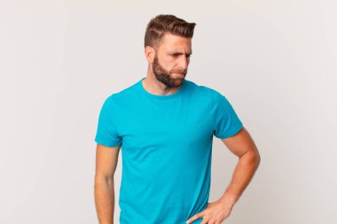 Genç ve yakışıklı bir adam üzgün, üzgün ya da kızgın hissediyor ve yan tarafa bakıyor. fitness konsepti