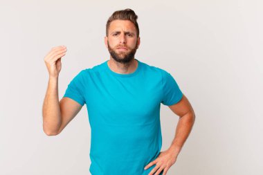 Genç yakışıklı adam kapiş ya da para hareketi yapıyor, sana ödemeni söylüyor. fitness konsepti