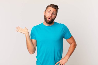 Genç, yakışıklı adam şaşırmış ve şok olmuş görünüyor. Çenesi düşmüş, elinde bir nesne var. fitness konsepti