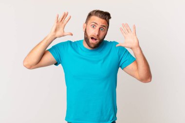 Genç yakışıklı adam ellerini havaya kaldırarak çığlık atıyor. fitness konsepti