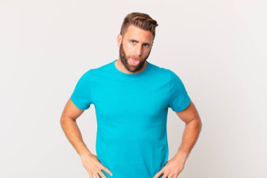 Genç ve yakışıklı bir adam tiksinmiş ve sinirlenmiş hissediyor ve dilini dışarı çıkarıyor. fitness konsepti