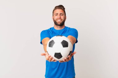 Genç ve yakışıklı bir adam arkadaşça gülümsüyor ve bir konsept sunuyor. futbol kavramı