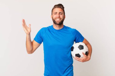 Genç yakışıklı adam kendini mutlu hissediyor ve inanılmaz bir şeye hayret ediyor. futbol kavramı