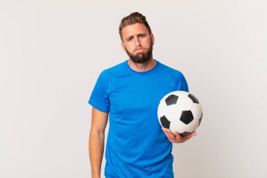 Genç ve yakışıklı bir adam üzgün ve mızmızlanıyor. Mutsuz bir bakışı var ve ağlıyor. futbol kavramı