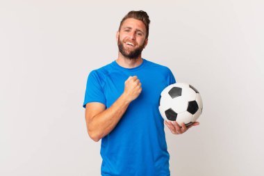 Genç yakışıklı adam kendini mutlu hissediyor ve bir meydan okumayla yüzleşiyor ya da kutluyor. futbol kavramı