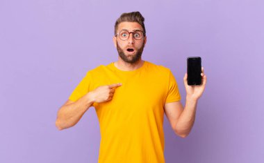 Şok olmuş ve ağzı açık, kendini işaret eden genç ve yakışıklı bir adam. hücre kavramı