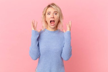 Genç ve güzel bir kadın ellerini havaya kaldırarak çığlık atıyor.