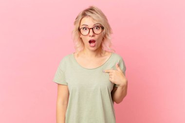Genç ve güzel bir kadın şok olmuş ve şaşırmış görünüyor, ağzı açık, kendini işaret ediyor.