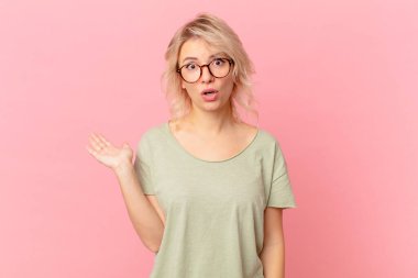 Genç ve güzel bir kadın şaşırmış ve şok olmuş görünüyor, çenesi düşmüş, elinde bir nesne tutuyor.