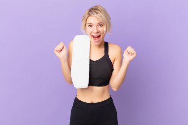 Genç ve güzel bir kadın şokta, gülüyor ve başarıyı kutluyor. fitness konsepti