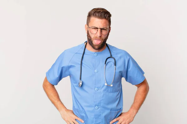 若いハンサムな男はうんざりしていらいらして舌を出す 看護師の概念 — ストック写真