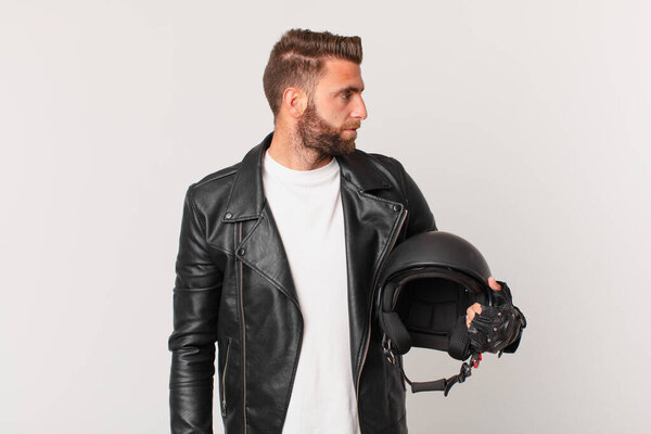 Молодой красивый мужчина с профильной точки зрения, думающий, воображающий или мечтающий. мотоциклетный шлем