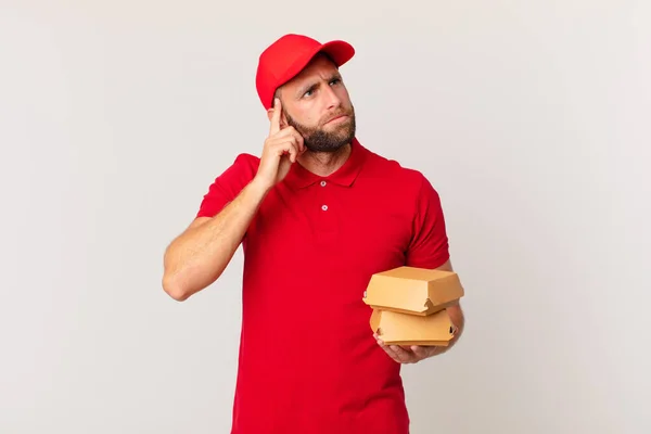 Young Handsome Man Thinking Feeling Doubtful Confused Burger Delivering Concept — Stok fotoğraf
