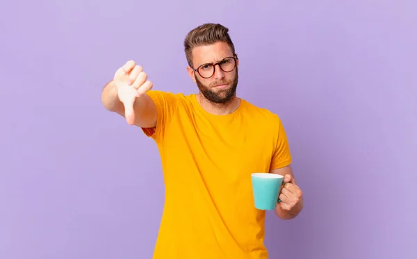 Young Handsome Man Feeling Cross Showing Thumbs Holding Coffee Mug — Φωτογραφία Αρχείου